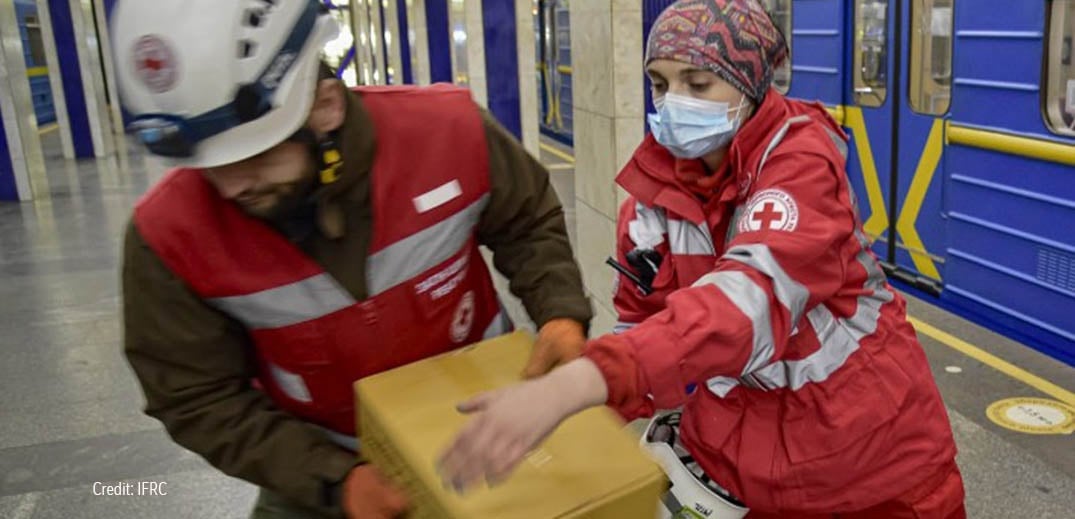 Colaboradores da Federação Internacional da Cruz Vermelha e do Crescente Vermelho a segurar caixa de donativos