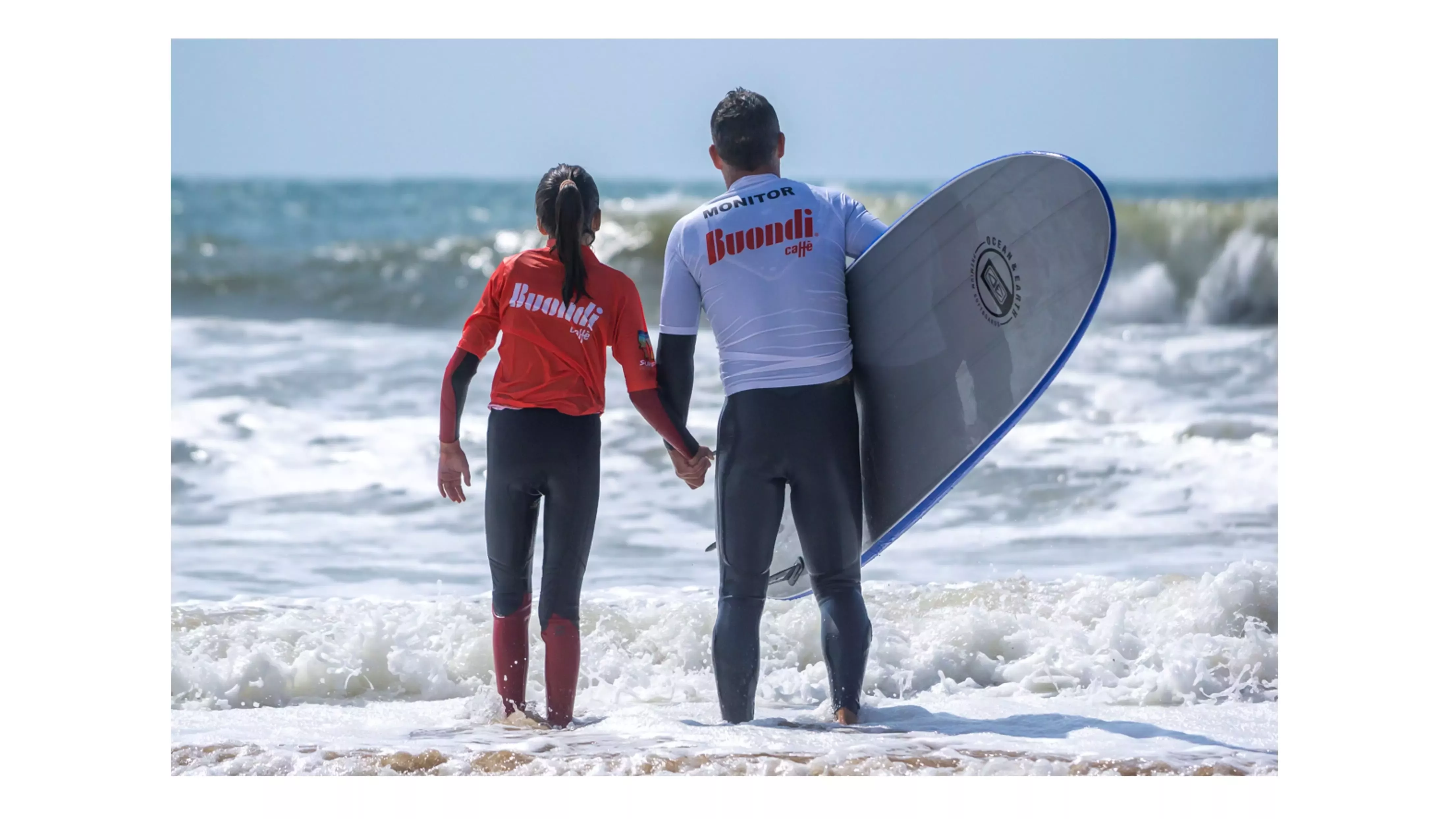 Menina junto a monitor com prancha de surf a entrar no mar