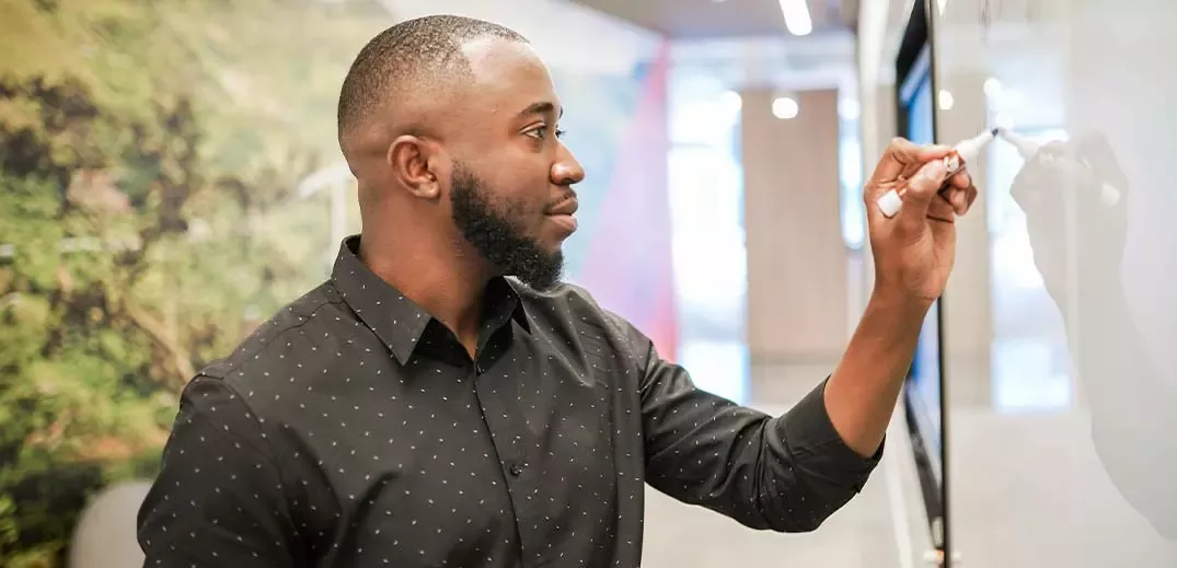 Colaborador de raça africana a escrever em quadro branco