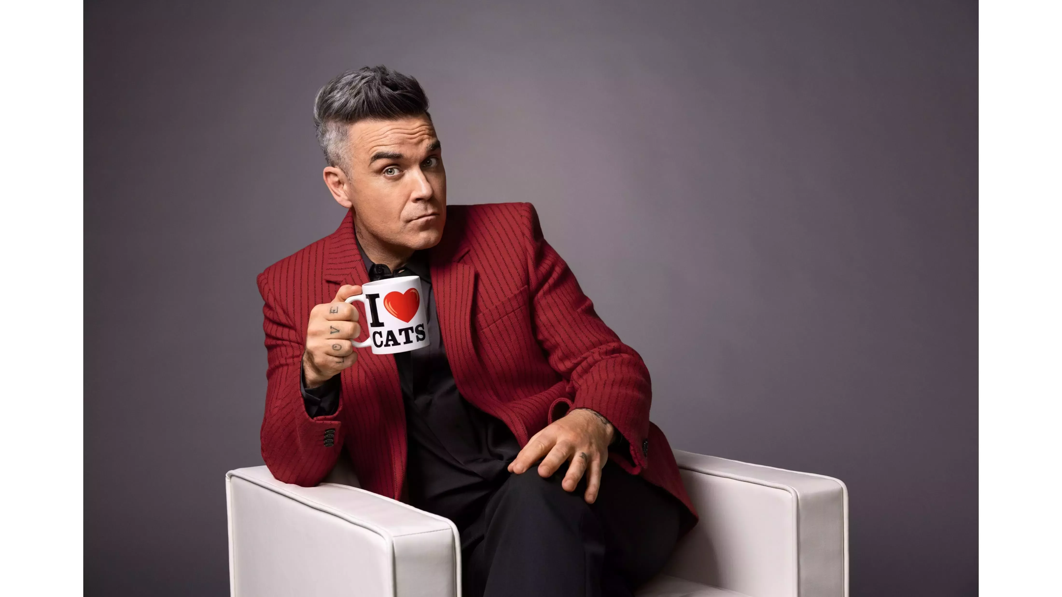 Robbie Williams com caneca “I Love Cats” na mão